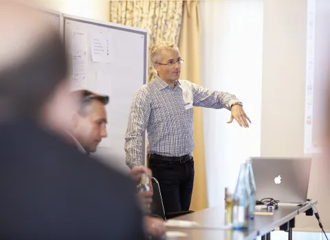 Männlicher Moderator eines Workshops von bad & heizung zum Thema Marketing mit Laptop vor einem Whiteboard.