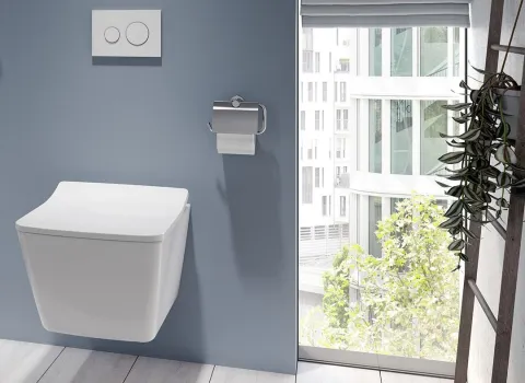 Das Bild zeigt ein stylisches Bad mit einem TOTO SP Wand-WC an einer hellblauen Wand, direkt neben einem großen Fenster mit Blick auf ein modernes Stadtgebäude.