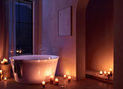 Runde, freistehende Design-Badewanne im Badezimmer mit Kerzenlicht und großem Fenster.