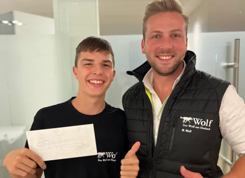 Ein Azubi hält neben Geschäftsführer Marius Wolf einen Gutschein in der Hand