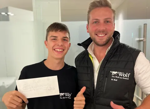 Ein Azubi hält neben Geschäftsführer Marius Wolf einen Gutschein in der Hand