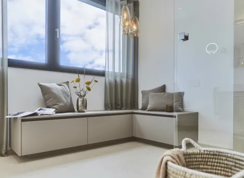 Gemütlicher Sitzbereich am Fenster als stilvolles Gestaltungselement im modernen Badezimmer.