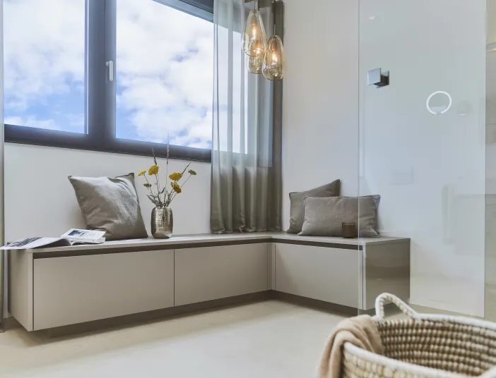 Gemütlicher Sitzbereich am Fenster als stilvolles Gestaltungselement im modernen Badezimmer.