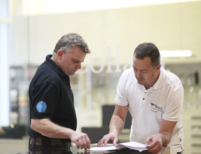 Zwei Mitarbeiter der Wolf GmbH besprechen technische Unterlagen in der Ausstellung.