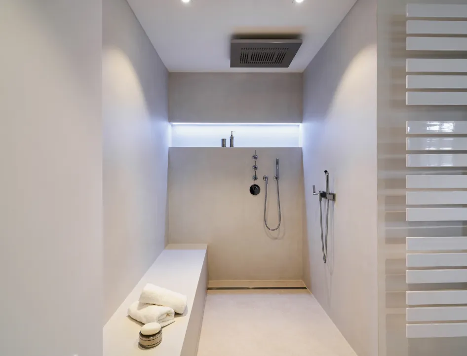 Begehbare Dusche mit Regendusche, Sitzbank und fugenarmer Wandgestaltung.