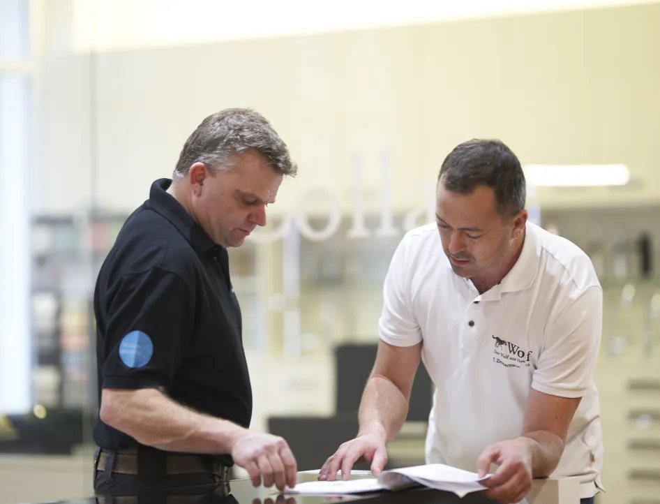 Zwei Mitarbeiter der Wolf GmbH besprechen technische Unterlagen in der Ausstellung.